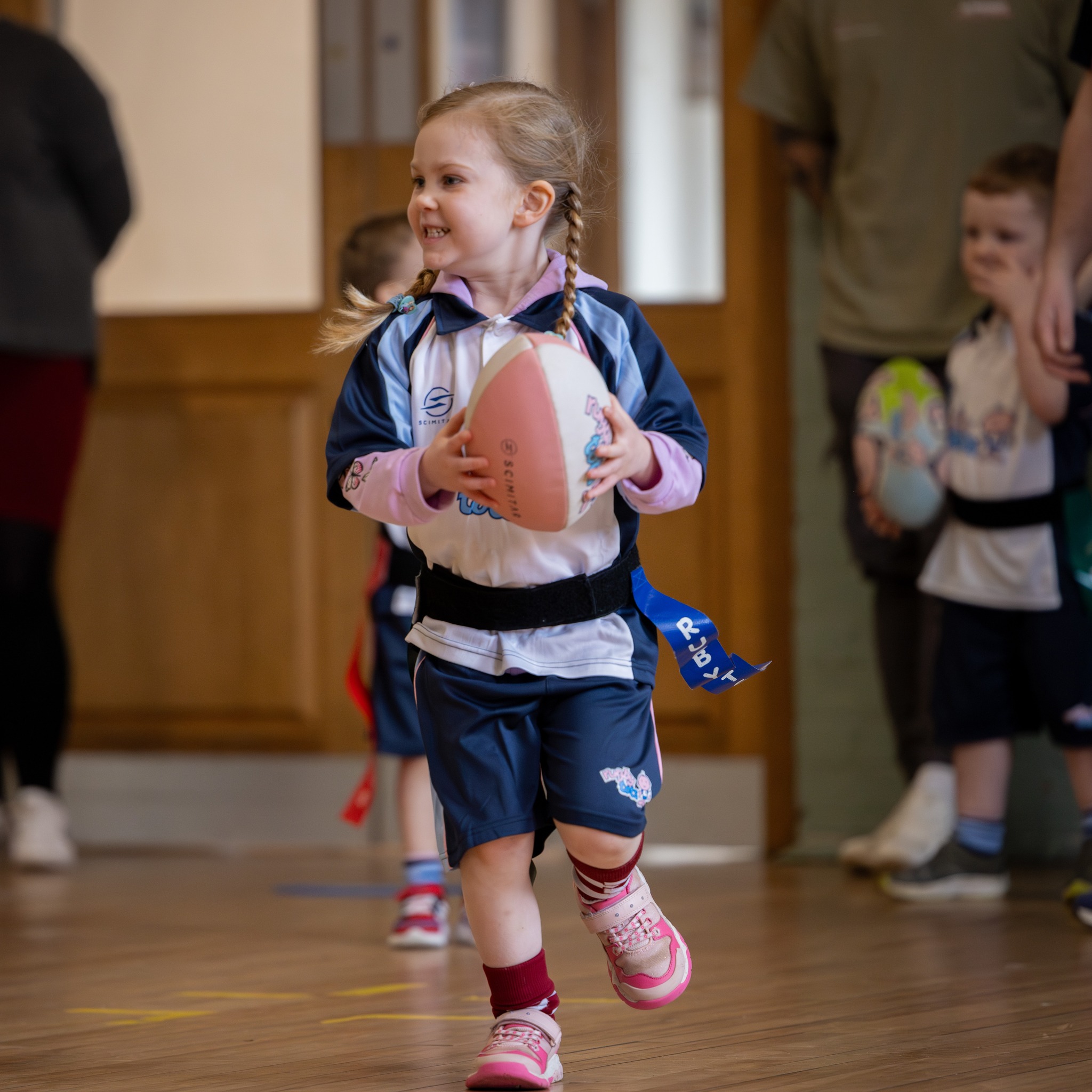 Bambina corre con il pallone da rugby durante la lezione