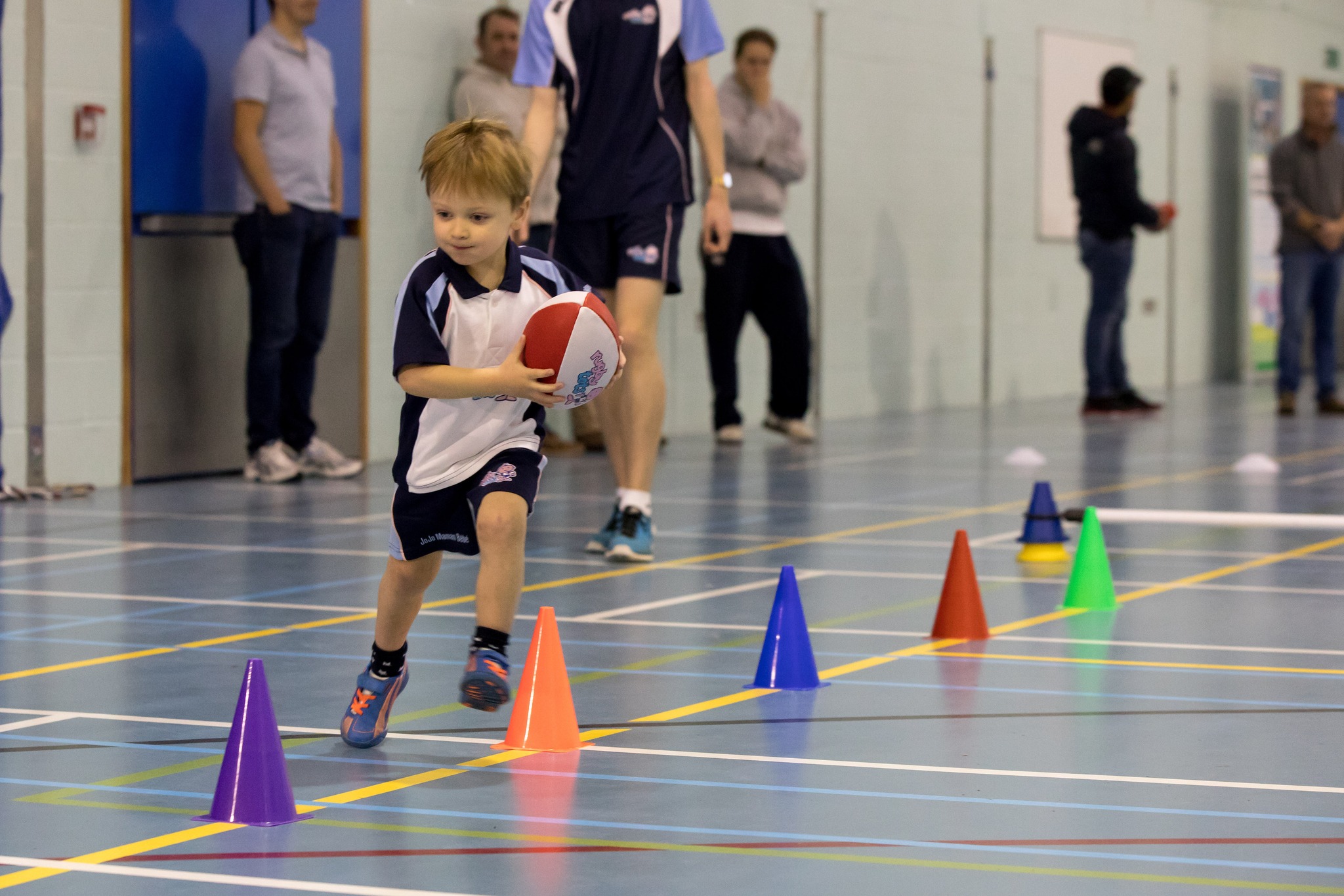 Bambino corre con il pallone tra i coni colorati