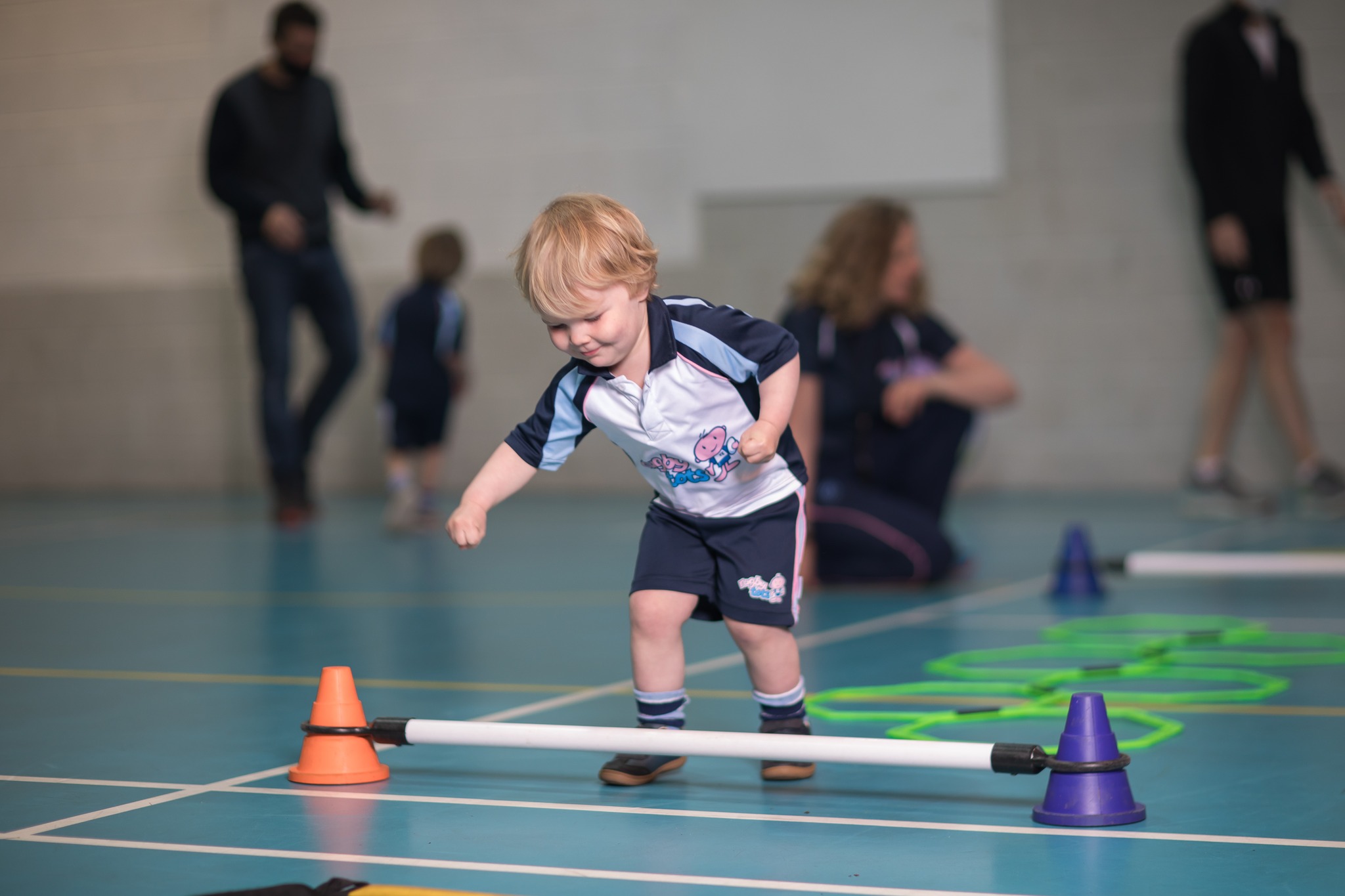 Bambino supera un percorso a ostacoli durante una lezione Rugbytots